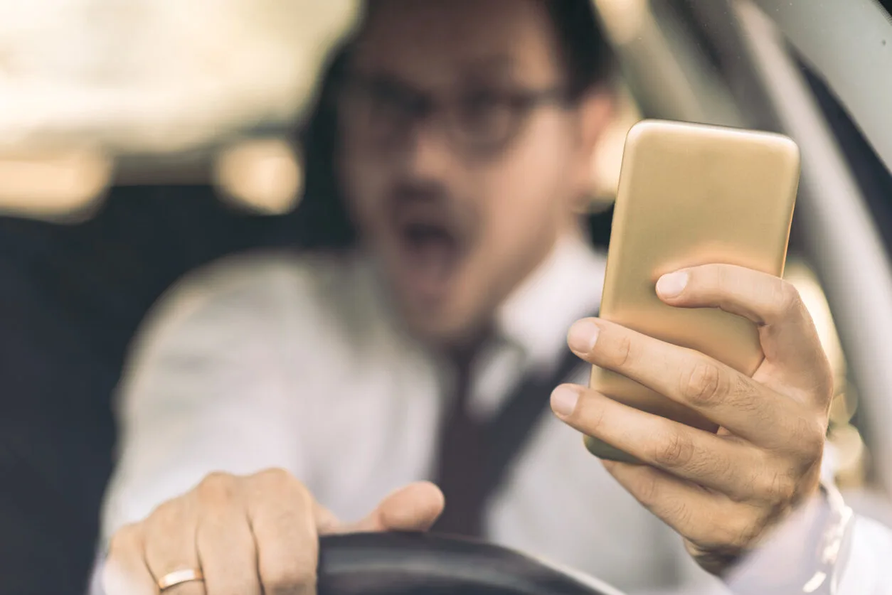 man driving a car while texting