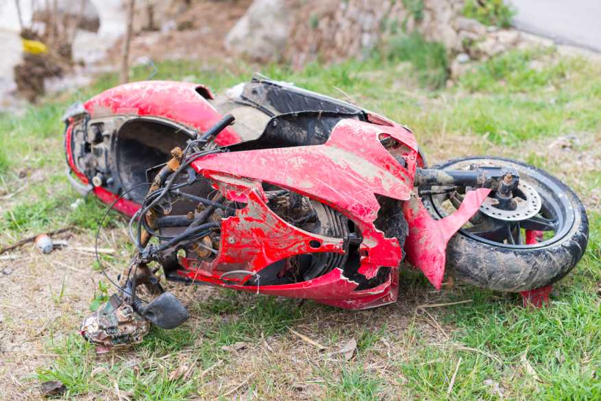 Wrecked red motorcycle on roadside grass following a common left-turn motorcycle accident in Texas.