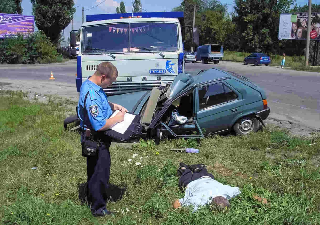 Houston police documenting evidence at a car crash site with damaged vehicle and injured person on grass.