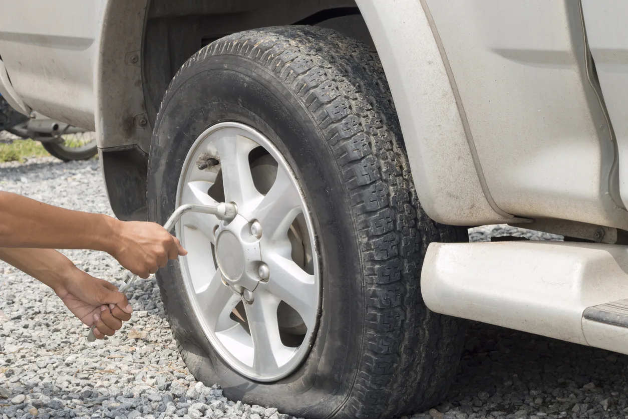A severely damaged car tire with shredded rubber strips, indicating a tire blowout, relevant to accidents and potential negligence.