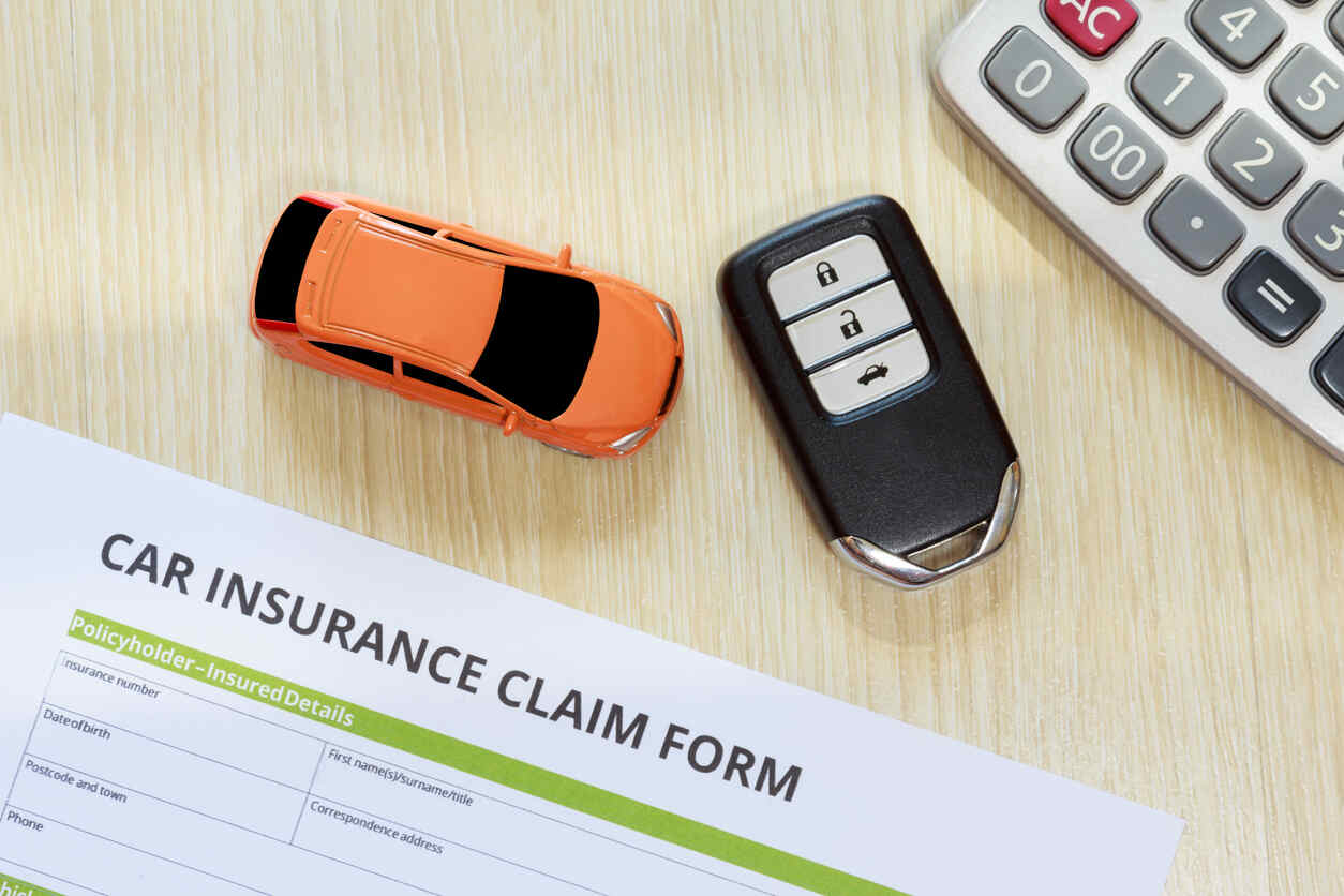 Items related to car insurance and claims, including a form, keys, and a toy car, illustrating the topic of hit-and-run incidents and insurance in Texas.