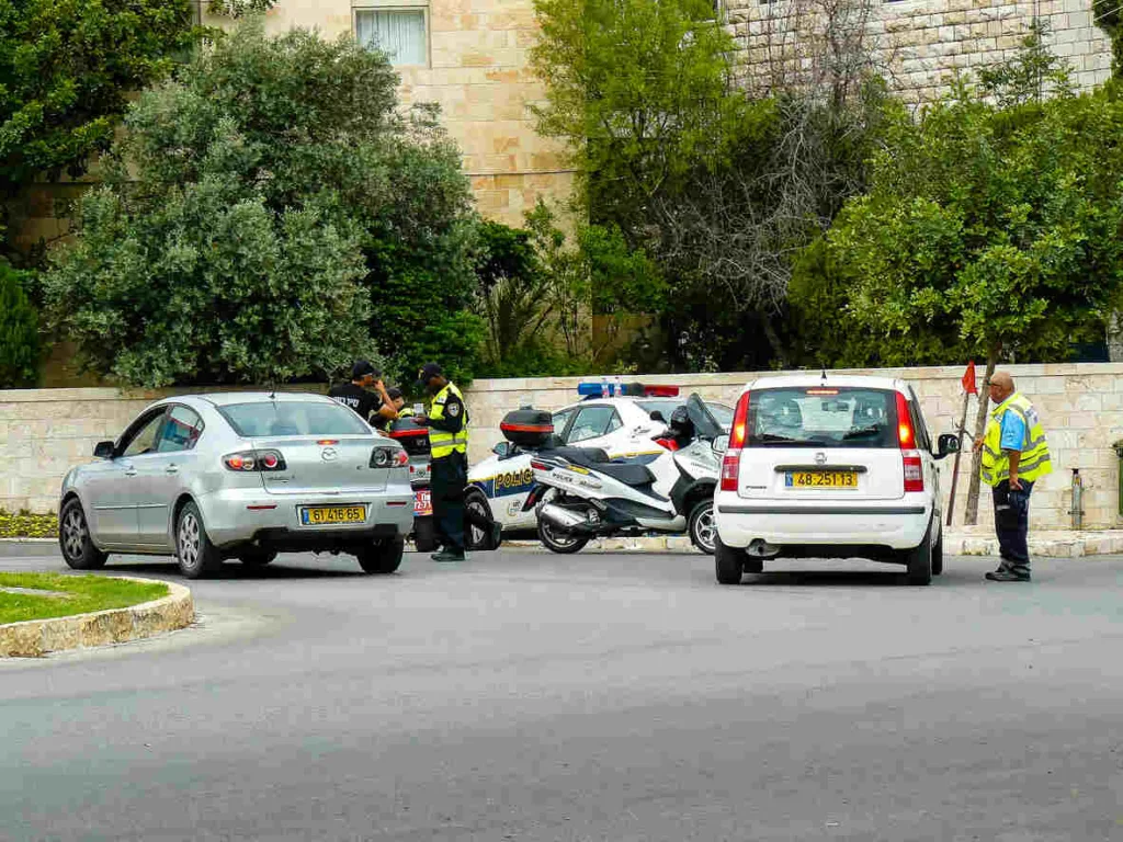 Police officers and drivers communicating at a car accident scene with police motorcycles and patrol cars present.