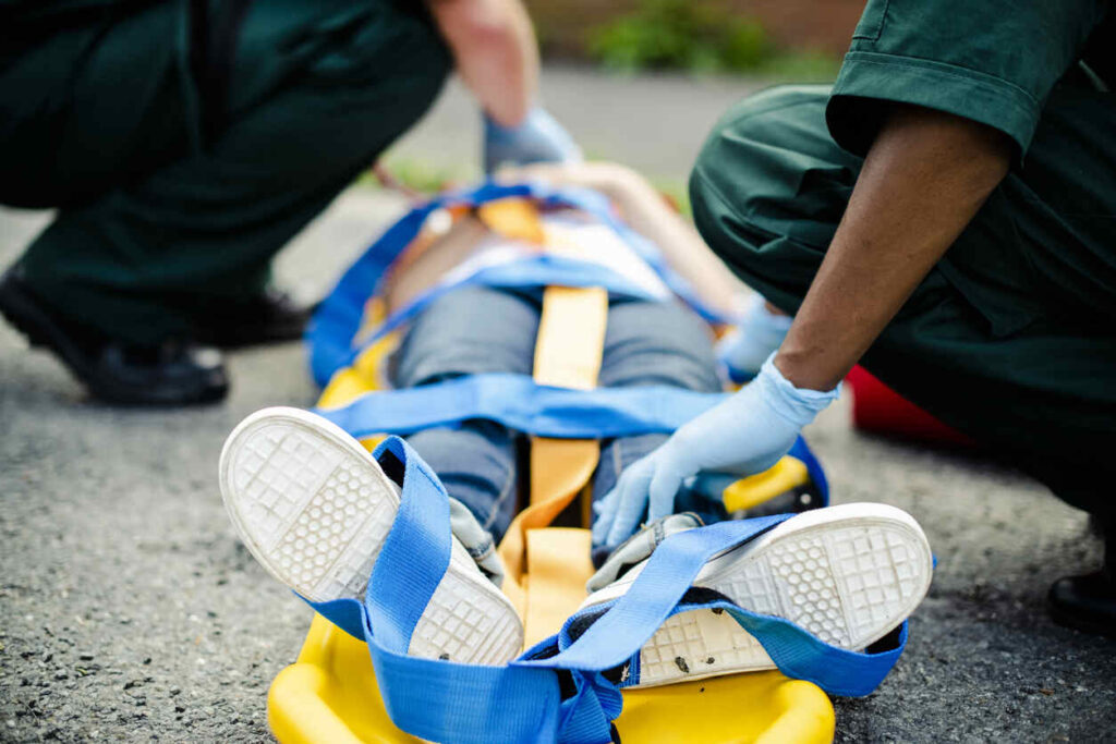 Emergency responders securing a patient on a stretcher for treatment of brain, spine, or burn injuries in a medical emergency