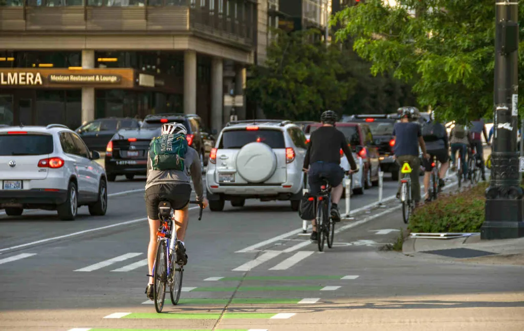 Group of e-bike riders navigating city traffic in dedicated bike lanes during rush hour, showcasing urban cycling safety.