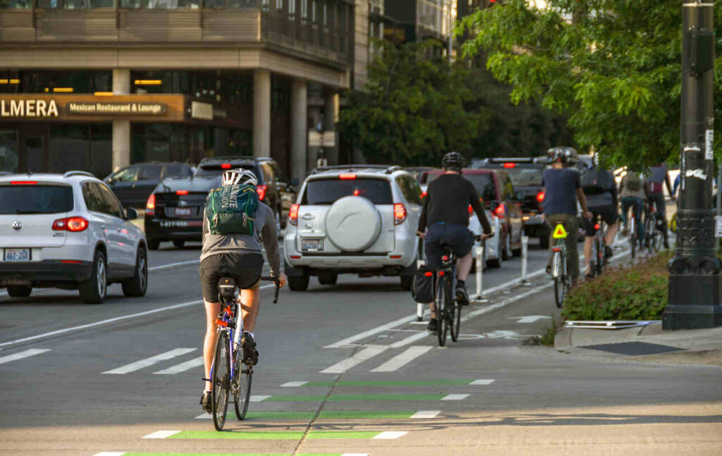 Group of e-bike riders navigating city traffic in dedicated bike lanes during rush hour, showcasing urban cycling safety.