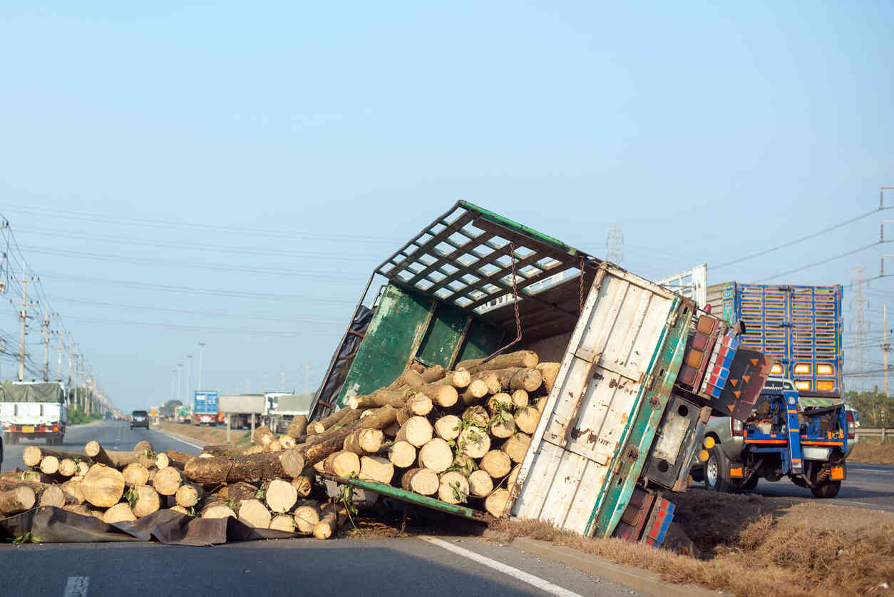  A semi-truck carrying a load of logs has overturned on a highway.