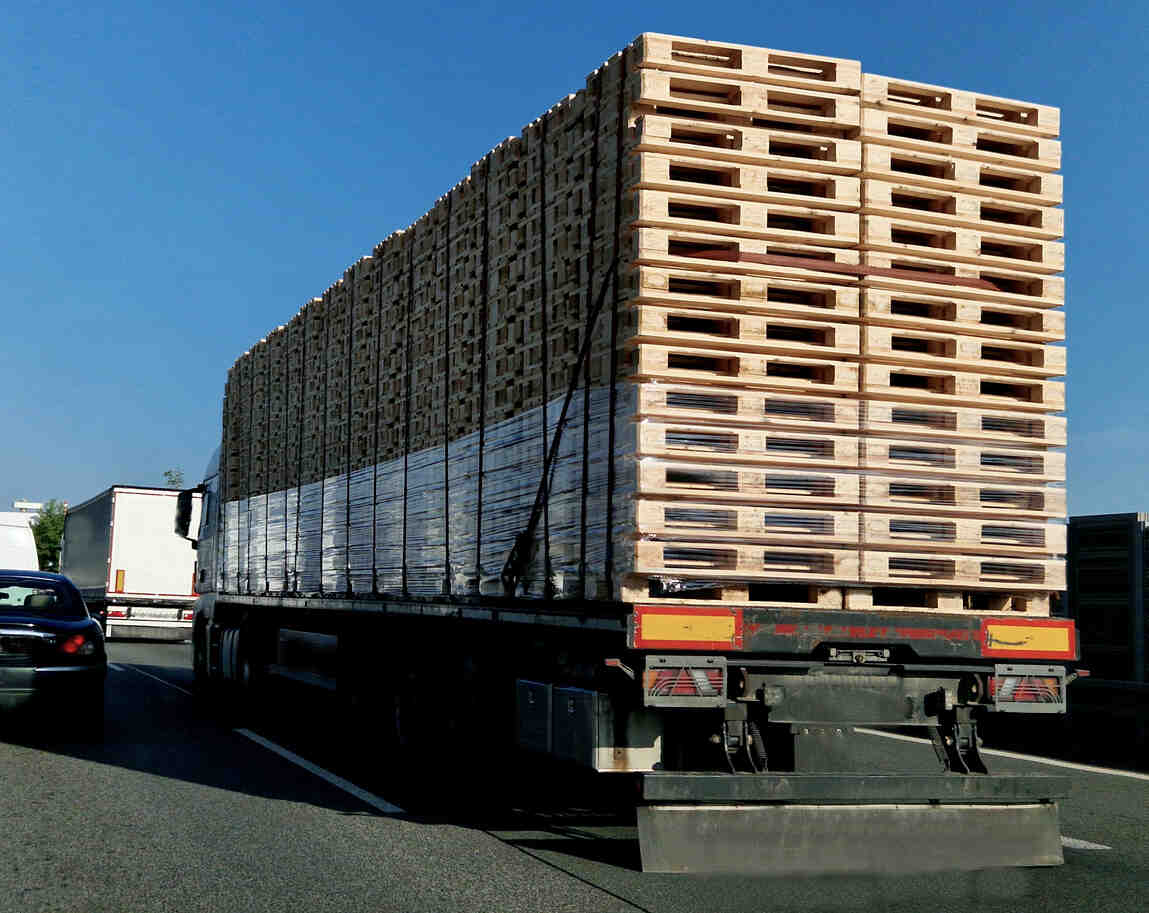 A heavily loaded tractor-trailer carrying pallets on a highway, representing the potential for a commercial trucking accident.