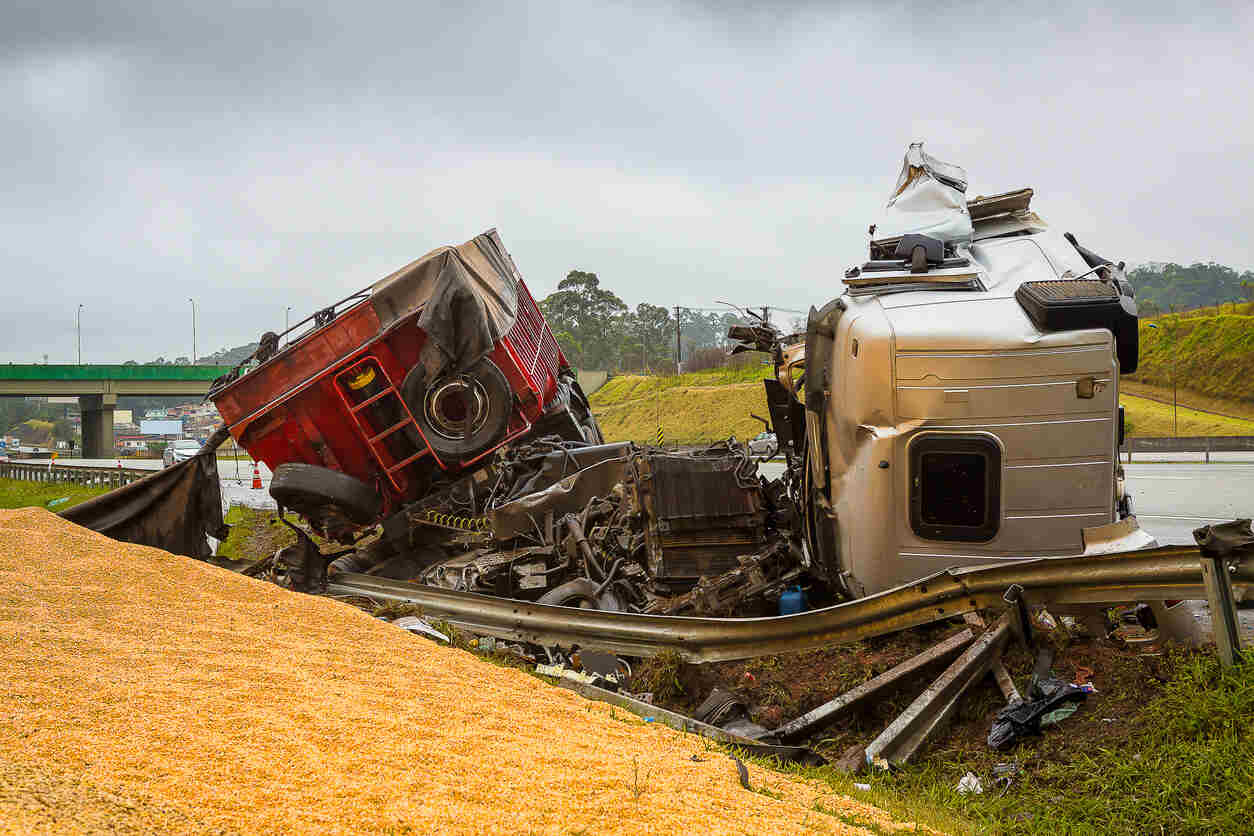An overturned semi-truck with a spilled load of grain lies on the side of a highway after an accident. The image shows the potential dangers of truck accidents in Wolfcamp Shale.